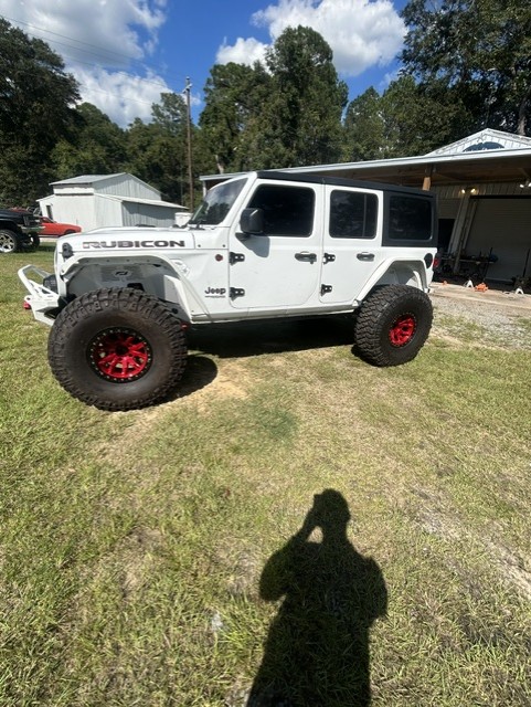 White Jeep Wrangler Rubicon on red beadlock wheels and off-road tires