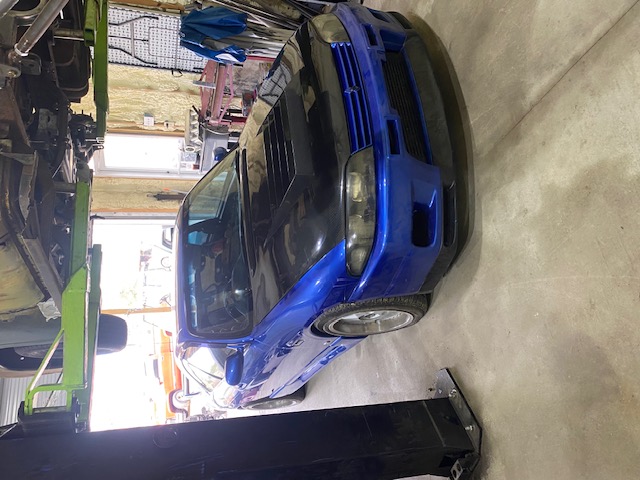Blue Nissan Skyline GT-R R33 on a two-post lift in the shop