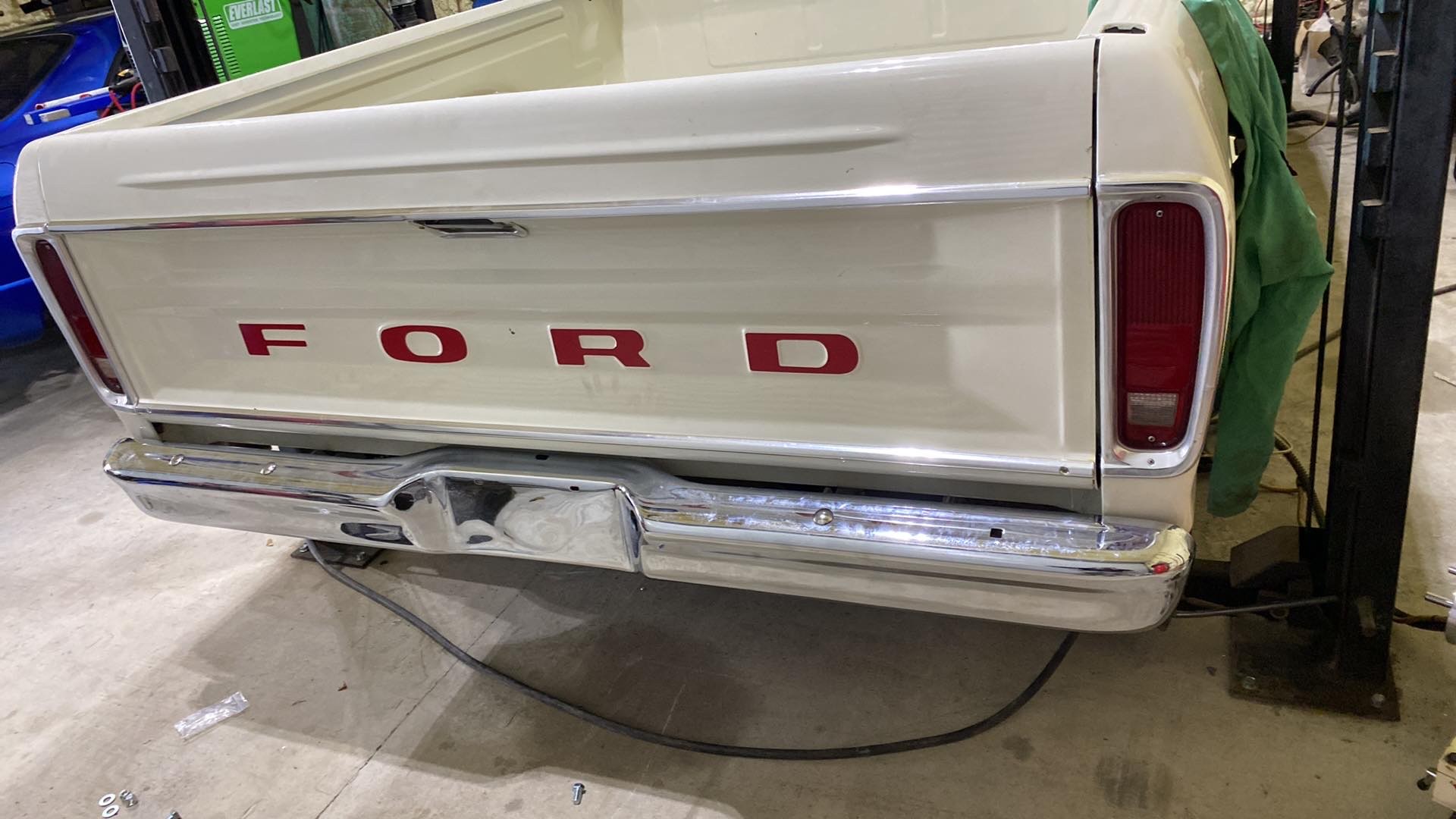 Restored Ford F-100 tailgate with red lettering and polished chrome bumper